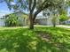 View of the front of the single-story home with a green lawn and mature trees and shrubbery at 4607 Pine Lake Dr, St Cloud, FL 34769