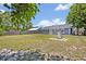 Spacious backyard with a gray house, fenced perimeter, mature trees, and utility access point at 6396 Bennett Ct, St Cloud, FL 34771