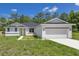 Charming single-story home with a two-car garage, white exterior, and a well-manicured front lawn at 7 Spring Pass, Ocala, FL 34472