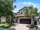 Charming two-story home featuring a tile roof, brick driveway and a two-car garage with tropical landscaping at 8897 Rhodes St, Kissimmee, FL 34747