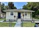 Charming single-story home with a blue door, complemented by a well-maintained fenced front yard and landscaping at 1602 W 12Th St, Sanford, FL 32771