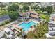 Aerial of a plus-shaped community pool, lounge seating, mature palms, and a clubhouse at 2343 St George Dr, Davenport, FL 33837