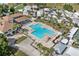 Aerial perspective of the community's plus-shaped pool, tables, palm trees, and a shaded clubhouse at 2343 St George Dr, Davenport, FL 33837