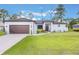 Charming single-story home with a well-manicured lawn, landscaped garden beds and a two-car garage at 2668 Coachman Dr, Deltona, FL 32738
