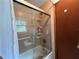 Tiled bathtub with shower featuring glass doors, and storage shelves at 2700 Cherokee Rd, St Cloud, FL 34772