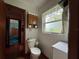 Cozy bathroom featuring a toilet, vanity, window with decor and a storage cabinet at 2700 Cherokee Rd, St Cloud, FL 34772