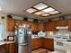 Functional kitchen with wooden cabinets, skylight and a suite of white appliances, offering both style and practicality at 2700 Cherokee Rd, St Cloud, FL 34772