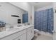 Well-lit bathroom featuring dual sinks, modern fixtures, and a decorative shower curtain at 2759 Slash Way, St Cloud, FL 34771