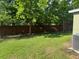 View of the green backyard framed by a brick privacy fence and mature trees at 2940 Tanzanite Ter, Kissimmee, FL 34758