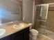 This bathroom features neutral walls, tile flooring, granite countertops, dual sinks, and glass enclosed shower at 2940 Tanzanite Ter, Kissimmee, FL 34758