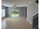 Living room with light gray walls, tan tile floors, ceiling fan, and sliding glass door to backyard at 2940 Tanzanite Ter, Kissimmee, FL 34758