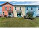 View of colorful townhomes, each with sliding glass doors and a small lawn area with chairs at 2993 Caribbean Soul Dr, Kissimmee, FL 34747