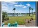 Scenic backyard view overlooking a tranquil lake, framed by lush greenery and palm trees under a sunny sky at 2993 Caribbean Soul Dr, Kissimmee, FL 34747