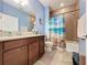 Well-lit bathroom features a single sink vanity and a bathtub with shower, accented by blue walls at 3193 Crispin Cir, Harmony, FL 34773