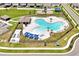 Aerial view features a resort-style community pool, surrounded by lush landscaping, lounge chairs, and shaded areas at 328 Lily Ln, Davenport, FL 33837