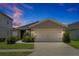 Charming home with a well-maintained lawn, a two-car garage, and a welcoming front entrance at twilight at 328 Lily Ln, Davenport, FL 33837