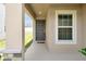 Inviting front porch with neutral paint and a gray front door and decorative stone columns at 328 Lily Ln, Davenport, FL 33837
