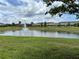 Scenic pond view with a fountain, green grass, and community buildings under a cloudy sky at 359 Arbor Lakes Dr, Davenport, FL 33896