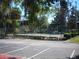 Community tennis court surrounded by landscaping and trees with parking nearby at 4085 Dijon Dr # 4085J, Orlando, FL 32808