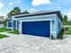 The side of this beautiful single-story home has an attached garage with a blue garage door and a lovely paver driveway at 41 Orchid Ct, Kissimmee, FL 34759