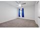 A bright bedroom with carpet flooring, a ceiling fan, and a window dressed in blue curtains at 4505 Hummingbird Ln, Haines City, FL 33844