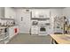 A kitchen featuring white cabinets, a range, refrigerator, and a door to another room at 512 Yellow Tail Pl, Chuluota, FL 32766