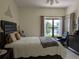 This bedroom offers a tranquil retreat with a serene lake view from the large window, plus neutral colors throughout at 5661 Parkview Lake Dr, Orlando, FL 32821