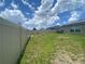 Fenced backyard with lawn, patio, and house with solar panels under a sunny sky at 568 Meadow Bend Dr, Davenport, FL 33837
