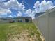 Fenced backyard with lawn, patio, and house with solar panels under a sunny sky at 568 Meadow Bend Dr, Davenport, FL 33837