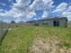 Fenced backyard with lawn, patio, and house with solar panels under a sunny sky at 568 Meadow Bend Dr, Davenport, FL 33837