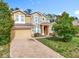 Two-story home showcasing a stone facade, complemented by a brick driveway and verdant landscaping at 771 Cavan Dr, Apopka, FL 32703