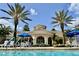 A beautiful clubhouse with arched entrances, a tile roof, and palm trees, viewed from the pool at 8401 Riverdale Ln # 8401, Davenport, FL 33896