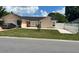 Tan home with a two car garage, manicured lawn, and lovely landscaping at 112 Rosewood Ct, Kissimmee, FL 34743