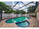 Screened pool with spa and slide, surrounded by a spacious brick patio and lush green landscaping at 112 Rosewood Ct, Kissimmee, FL 34743