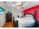 Bedroom with red accent wall, ceiling fan, television, and dark wood furniture at 113 Candlewood Ct, Kissimmee, FL 34743
