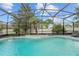Screened in pool with a waterfall feature and lounge chairs overlooking the green landscaping at 113 Candlewood Ct, Kissimmee, FL 34743