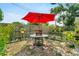 A delightful backyard with a red umbrella shading a patio table with seating and green fence at 1422 Indiana Ave, St Cloud, FL 34769