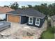 Side view of a newly built home with a dark blue exterior and a boarded-up garage at 1522 Pine St, Orlando, FL 32824