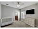 Bright bedroom with a ceiling fan, a TV, a white crib and dresser, and an en-suite bathroom at 1607 Wilson Ave, Orlando, FL 32804