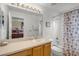 Bright bathroom featuring a vanity with sink, large mirror, and bathtub with seashell-patterned shower curtain at 195 Hideaway Beach Ln, Kissimmee, FL 34746
