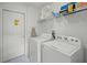 Well-lit laundry room equipped with a washer, dryer, and overhead shelving for storage solutions at 195 Hideaway Beach Ln, Kissimmee, FL 34746