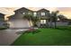 Two-story home showcasing a well-manicured front yard with lush green grass and mature palm trees at 2024 Bearing Ln, Kissimmee, FL 34744