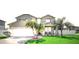 Beautiful two-story home with a manicured lawn, palm trees, and a two-car garage at 2024 Bearing Ln, Kissimmee, FL 34744