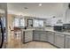 Bright kitchen with gray cabinets, stainless steel dishwasher, and an open view to the dining area at 2024 Bearing Ln, Kissimmee, FL 34744