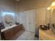 Bathroom featuring tiled walls, double sinks with granite counters, wooden cabinets and a decorative mirror at 204 Canary Island Cir, Davenport, FL 33837