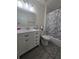 Well-lit bathroom with white vanity, tile flooring, and shower with decorative curtain at 204 Canary Island Cir, Davenport, FL 33837