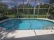 The turquoise swimming pool has a screened enclosure and faces a wooded backyard at 204 Canary Island Cir, Davenport, FL 33837