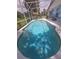 A turquoise in ground pool in a screened in enclosure with patio furniture nearby at 204 Canary Island Cir, Davenport, FL 33837
