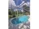 A crystal clear pool has a screened enclosure with patio furniture under an umbrella nearby at 204 Canary Island Cir, Davenport, FL 33837