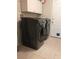 Modern laundry room featuring sleek, dark-colored washer and dryer units, with white cabinets for storage, and tiled floors at 2141 Fawn Meadow Cir, St Cloud, FL 34772